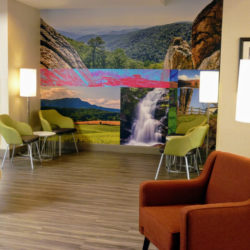 a picture of the lobby at the newly renovated Clarion Pointe Harrisonburg featuring a wall mural showing an assortment of local photography