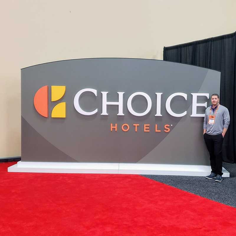 Picture of Jackson Hotel Management President Brent C Jackson standing next to the Choice Hotels sign at conference