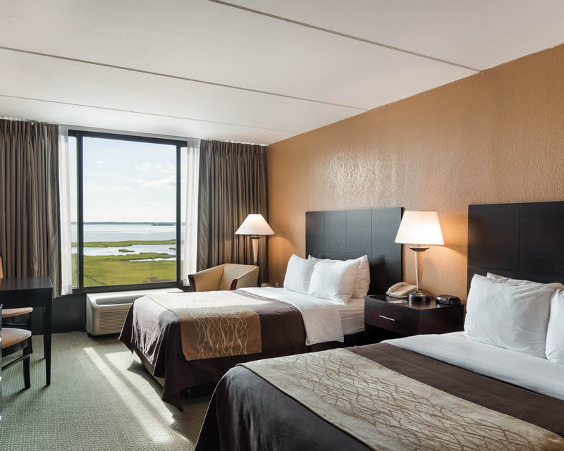 a picture of a guest room with two beds overlooking the bay at the comfort inn gold coast in ocean city, md